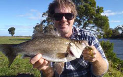 A young fisherman holding up a large estuary perch